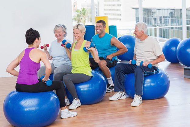 people lifting dumbbells in gym class