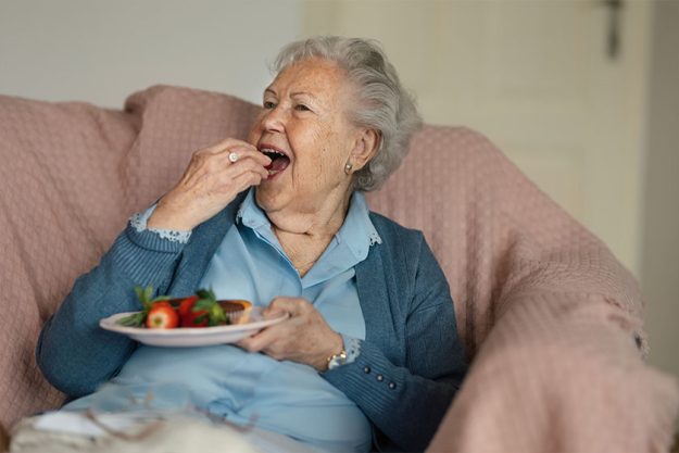 senior woman resting her home eating strawberries senior woman resting her home eating strawberries