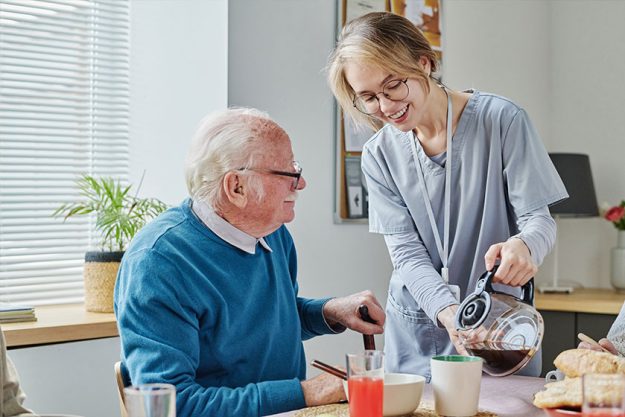 young caregiver pouring coffee teapot senior man