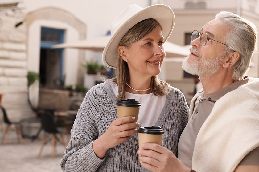 affectionate senior couple coffee walking outdoors space text