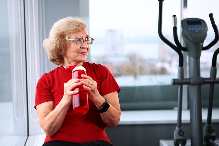 an elderly woman holds a water bottle in the gym active retirement lifestyle concept copy 