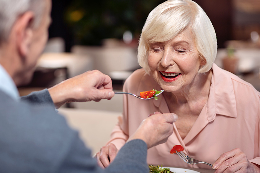 charming mature woman eating from mans fork