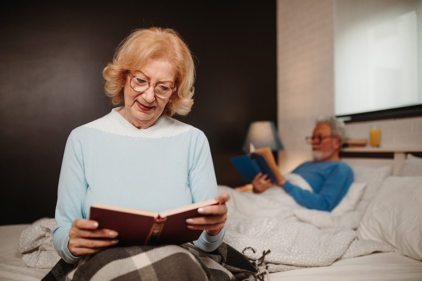close shot blonde elderly woman glasses while reading book while