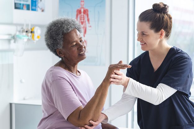 diverse senior female patient exercising hand female doctor advising hospital diverse senior female patient exercising hand female doctor advising hospital