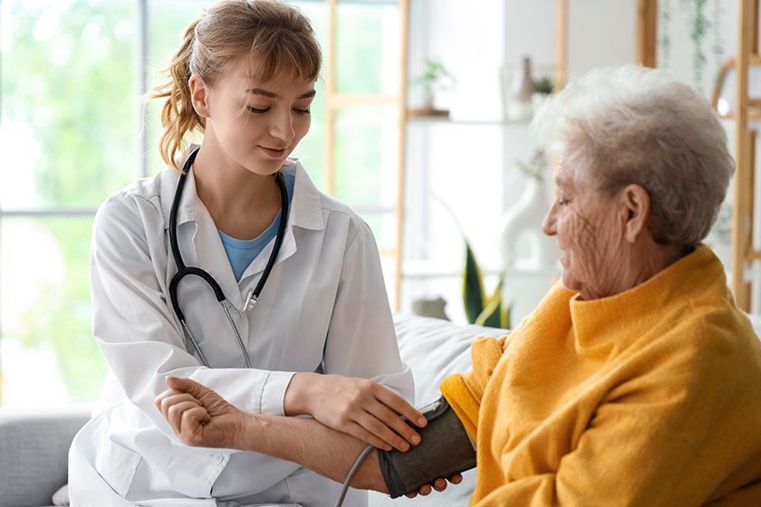 doctor measuring blood pressure senior woman home