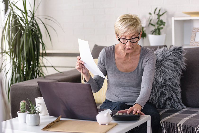 elderly retired woman looking papers calculating mortgages savings expenses planning