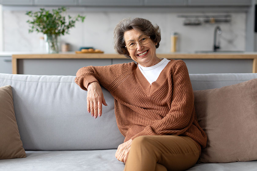 happy senior lady resting sofa smiling camera enjoying domestic comfort