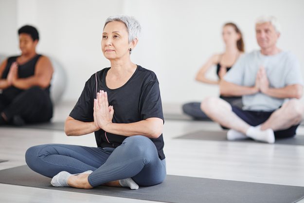 mature woman doing yoga in class mature woman doing yoga in class