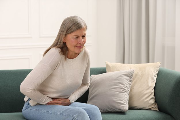 menopause woman suffering abdominal pain sofa home menopause woman suffering abdominal pain sofa home