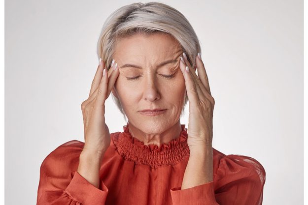 one mature woman suffering headache looking stressed while posing grey