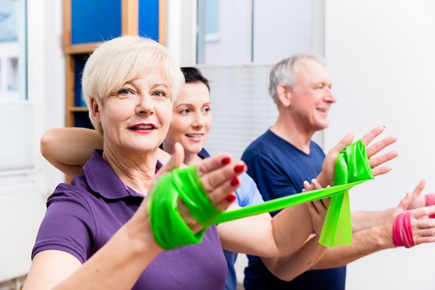 physio showing senior couple how to use rubber band as expander physio showing senior couple how to use rubber band as expander