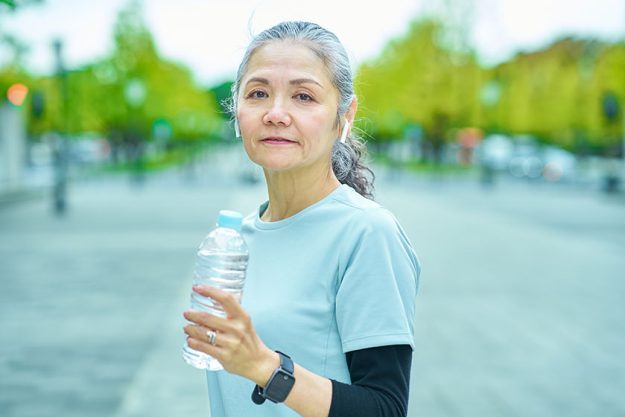 senior woman drinking water plastic bottle outdoors