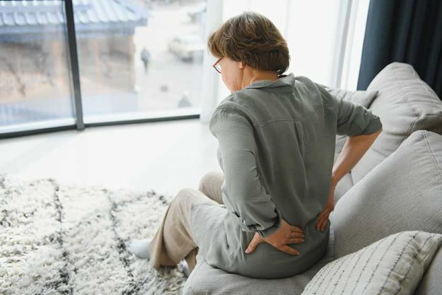 senior woman suffering back pain sofa home