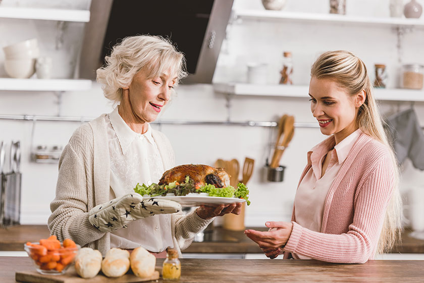 smiling mother daughter holding plate tasty turkey thanksgiving day