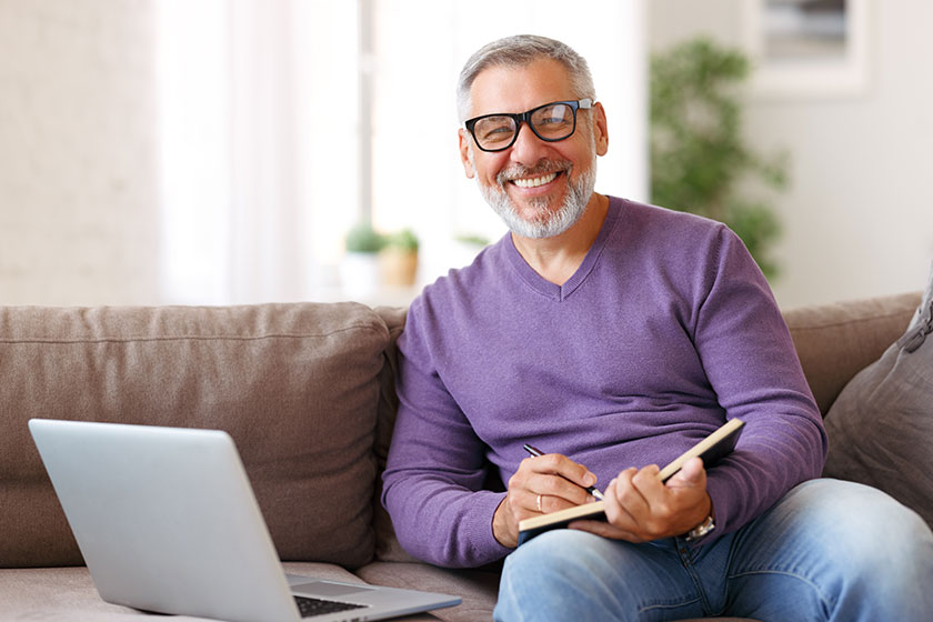 handsome positive senior man wearing glasses working remotely while sitting