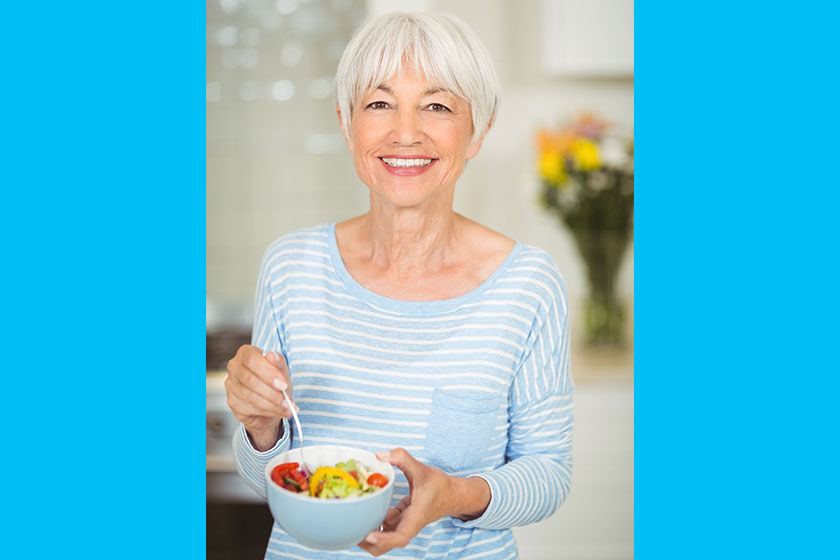 happy senior woman holding bowl of vegetable salad