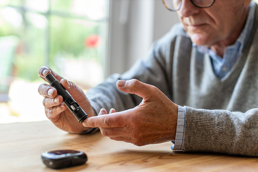mature man checking blood sugar level glucometer