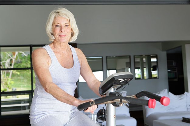 mature woman using an exercise bike at home mature woman using an exercise bike at home