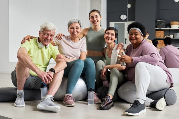 portrait fitness instructor smiling camera her group health studio