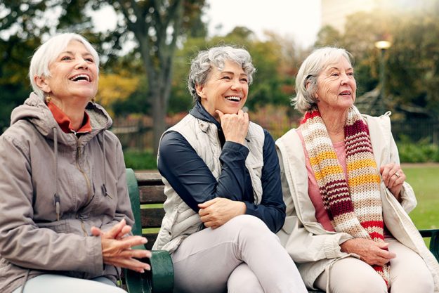 senior women friends pointing park view retirement smile garden nature