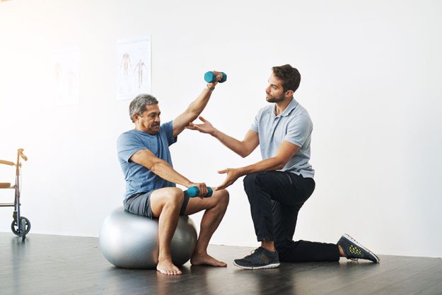 slow easy movements young male physiotherapist helping mature male patient slow easy movements young male physiotherapist helping mature male patient