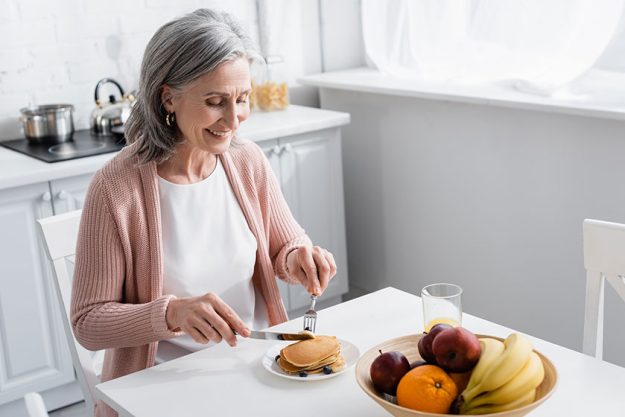 smiling woman cutting pancakes ripe fruits kitchen smiling woman cutting pancakes ripe fruits kitchen