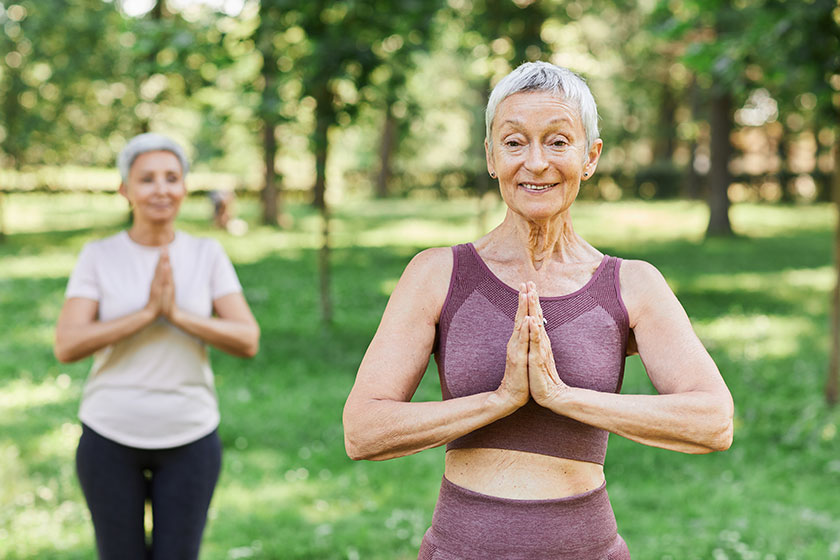 waist portrait active senior woman enjoying yoga outdoors smiling camera