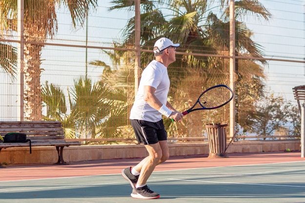an elderly man plays tennis on an outdoor court an elderly man plays tennis on an outdoor court