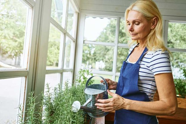 beautiful middle aged caucasian woman watering plants