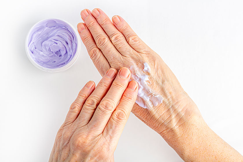 elderly woman creaming her hands close cosmetic moisturizing care old