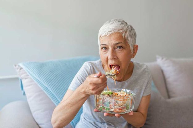 elegant mature woman sitting bed eating fresh salad sofa elegant mature woman sitting bed eating fresh salad sofa
