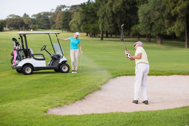 golfer playing on sand trap by woman