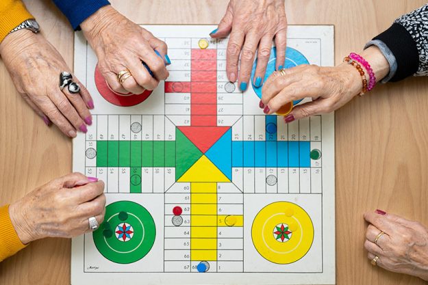 group unrecognizable senior woman playing classic game ludo parchis nursing