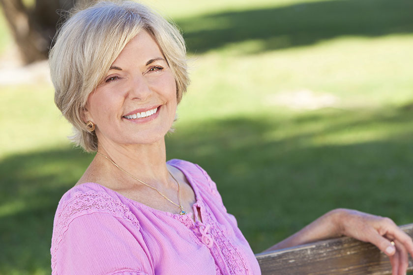 happy senior woman sitting outside smiling
