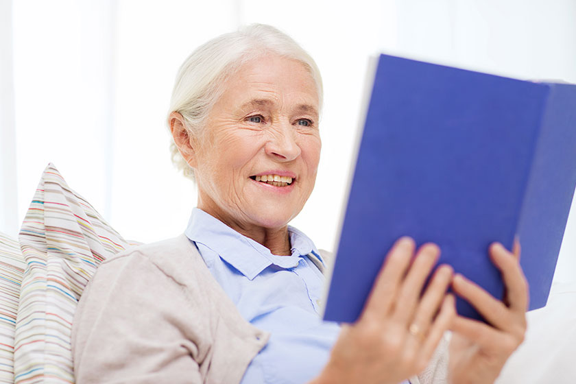 happy smiling senior woman reading book at home