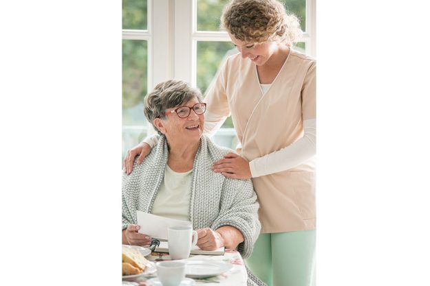 positive senior lady siting table smiling her young nurse positive senior lady siting table smiling her young nurse