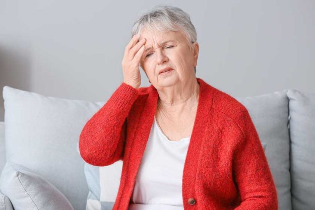 senior woman suffering from headache at home