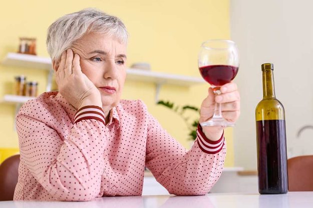 stressed senior woman drinking wine home
