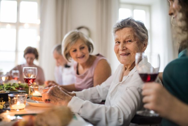 An,Elderly,Women,With,A,Family,Sitting,At,A,Table