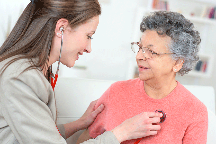 female caregiver examining senior woman with stethoscope