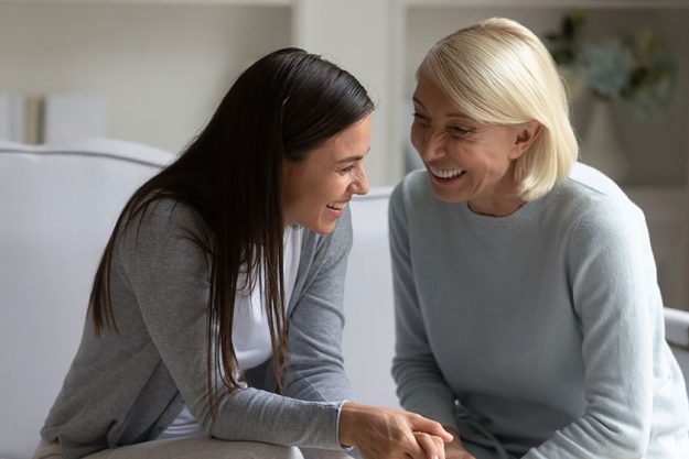 happy mature mother and adult daughter relax at home talking