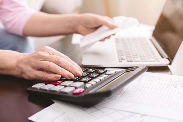 senior woman calculating taxes at home using calculator