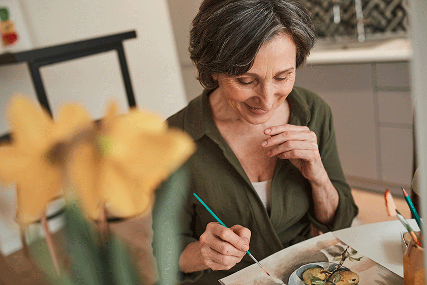 woman sitting calmly at the table and drawing great picture with watercolors