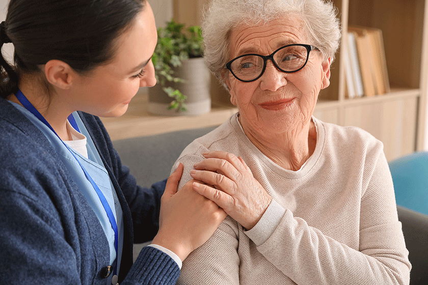 young caregiver hugging senior woman home closeup