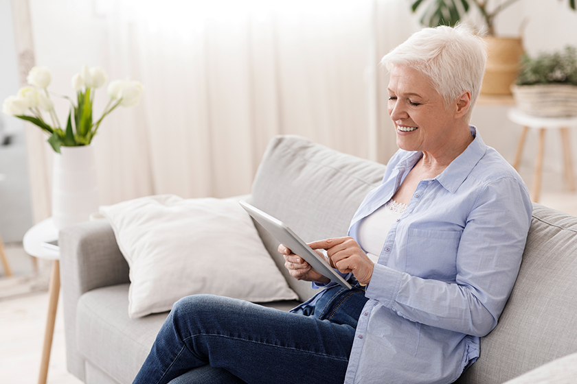 elderly woman spending time with digital tablet on couch in living room