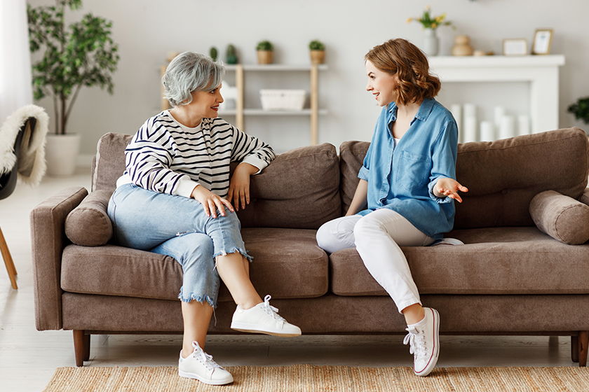 full length young woman smiling talking senior mother while sitting full length young woman smiling talking senior mother while sitting