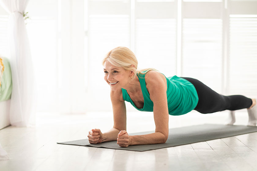 Home training concept smiling senior woman doing elbow plank yoga Home training concept smiling senior woman doing elbow plank yoga