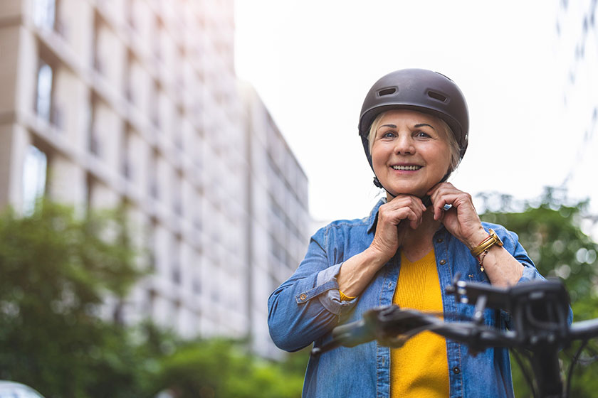 Portrait senior woman wearing helmet while riding bicycle city