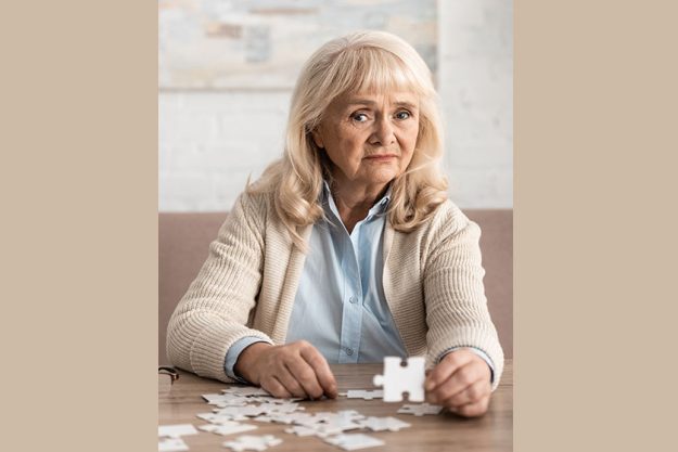 selective focus confused retired woman alzheimer holding puzzle piece