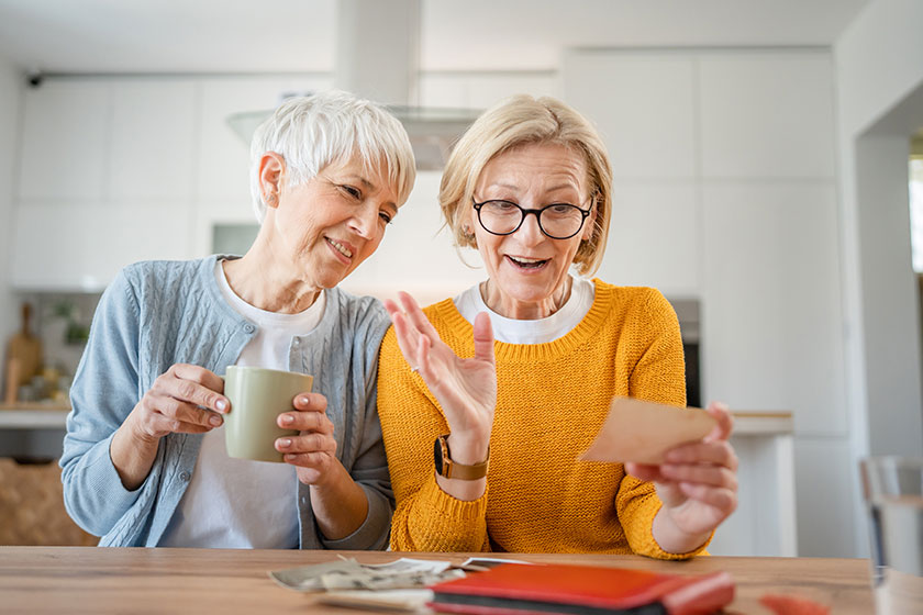 senior mature women friends sisters looking family photos album two